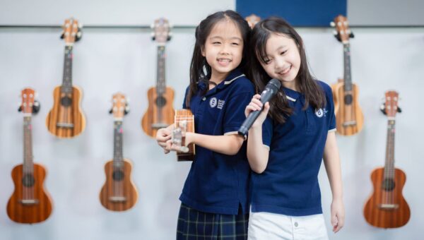 CR5_0587 BASIS International School Bangkok students holding ukuleles beside an instrument rack