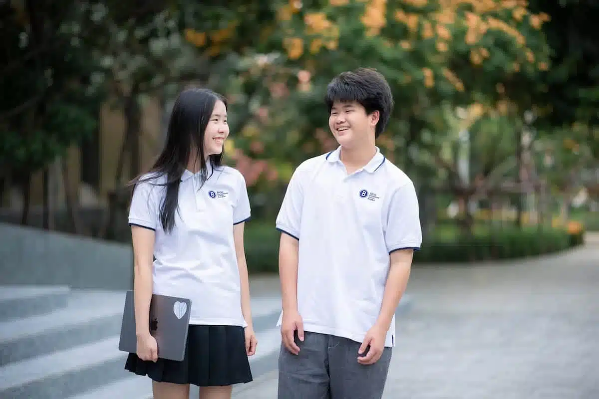 นักเรียนมัธยมปลายสองคนเดินคุยกันในวิทยาเขตโรงเรียนนานาชาติ BASIS กรุงเทพฯ พระราม 2