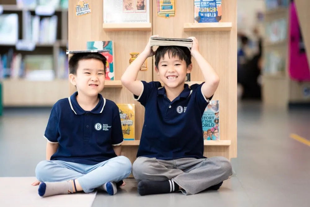 two young students at BASIS International School have fun in the library.