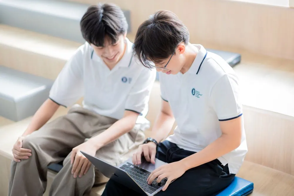 two BASIS International School students work on a laptop together