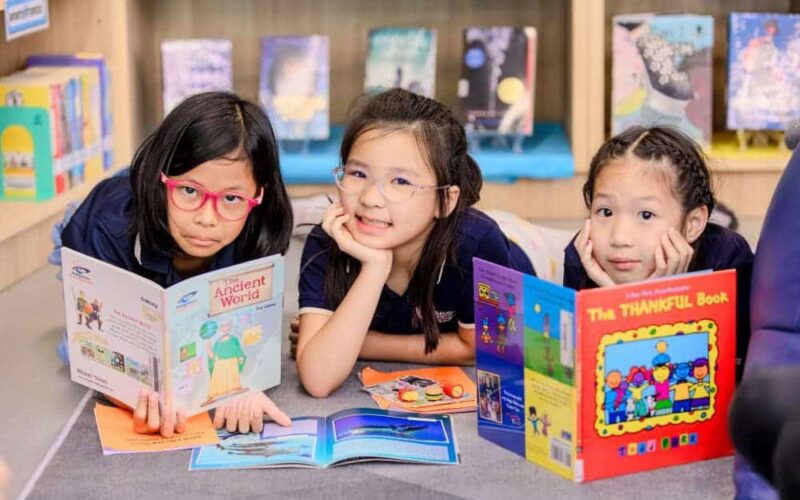 smiling-students-holding-up-books Smiling BASIS International School Bangkok students holding up books