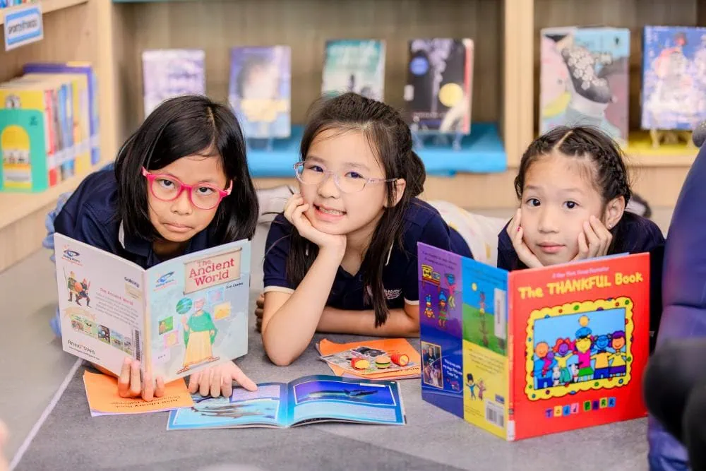 Smiling students holding up books